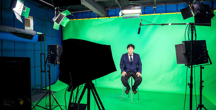 Pasti kamu sudah tidak asing lagi dengan yang namanya green screen di dalam dunia perfilman. Teknik yang satu ini digunakan filmmaker untuk menggabungkan dua gambar ke dalam satu frame, sehingga efek visual terlihat lebih nyata. Nah, di balik itu semua, ternyata ada beberapa teknik shooting menggunakan green screen agar tampak lebih halus. Bagi kamu yang sedang kursus film, wajib hukumnya untuk mengetahui beberapa teknik tersebut. Intip yuk! Menggunakan background berwarna hijau murni Hal pertama yang harus diperhatikan dalam pemilihan background adalah warna hijau murni. Di mana warna hijau murni ini tidak mengandung warna lainnya. Ini dimaksudkan supaya tidak merusak warna dari sang objek. Misalnya saja kamu menggunakan warna hijau tua, akan membuat warna kulit dari objek berubah menjadi transparan. Kemudian hal tersebut juga akan mengganggu proses editing karena kesulitan menghilangkan warna hijau. Ini semua diakibatkan lantaran dalam warna hijau tua terdapat kandungan warna coklat. Memberikan jarak antara objek dengan kamera Teknik kedua yang wajib diperhatikan adalah memberikan jarak antara objek dan kamera. Tujuannya adalah untuk menghindari kebocoran lampu yang mengakibatkan pantulan terlihat pada green screen terhadap tubuh objek yang disorot. Hal ini juga berhubungan dengan yang namanya angle kamera. Pastikan untuk memilih posisi kamera yang terbaik supaya semua sudut bisa terlihat jelas. Agar tak terjadi kesalahan, kamu bisa membuat storyboard terlebih dulu untuk menentukan di mana posisi kamera yang tepat. Memakai tracking point kalau terdapat pergerakan Selanjutnya adalah menggunakan tracking point. Teknik satu ini dijalankan ketika kamu akan memasukkan sebuah efek di dalam video, misalnya saja seperti tulisan atau gambar. Dengan cara ini, apa yang kamu konsepkan akan memiliki sebuah acuan untuk melakukan sebuah gerakan. Menyesuaikan wardrobe yang digunakan Trik lainnya untuk melakukan shooting memakai green screen adalah menyesuaikan pakaian yang dipakai oleh objek. Untuk model bajunya sebenarnya tergantung dari kebutuhan. Namun untuk warnanya usahakan tidak mengandung warna hijau dan biru. Alasannya agar objek atau benda yang berwarna hijau menghilang saat di video. Memastikan tekstur dan pencahayaan yang rata Kamu juga wajib memperhatikan tekstur serta pencahayaan. Di mana kamu sangat perlu untuk memastikan terlebih dulu apakah tekstur dan pencahayaan rata atau tidak. Jika rata, maka objek di dalam green screen akan terlihat lebih rapi. Sedangkan kalau tekstur dan pencahayaan tidak rata, maka objek di dekat green screen akan mengalami ketidaksempurnaan saat proses editing mengeliminasi warna hijau. Props and set Tips lainnya adalah memastikan banyaknya barang nyata yang terdapat dalam green screen. Sebab, jika barang nyata semakin banyak, maka akan semakin sedikit Anda melakukan pengeditan supaya tampak lebih real. Maka dari itu, letakkan beberapa elemen nyata agar tidak menghabiskan waktu dalam mengedit video kamu. Bagi kamu yang ingin tahu lebih banyak mengenai trik dan tips shooting green screen, yuk daftar kursus film atau kuliah film di sekolah film International Design School. Untuk lebih lengkapnya, bisa langsung cek website atau linktree di bio Instagram IDS!